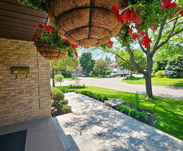 Horvath Landscapes front porch view with a clean concrete entry walkway and landscaped curb appeal under mature trees.