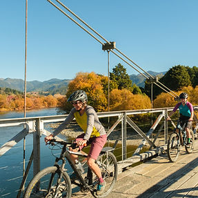E-bike reizigers steken brug over in herfstlandschap bij Arrowtown, Zuidereiland Nieuw-Zeeland