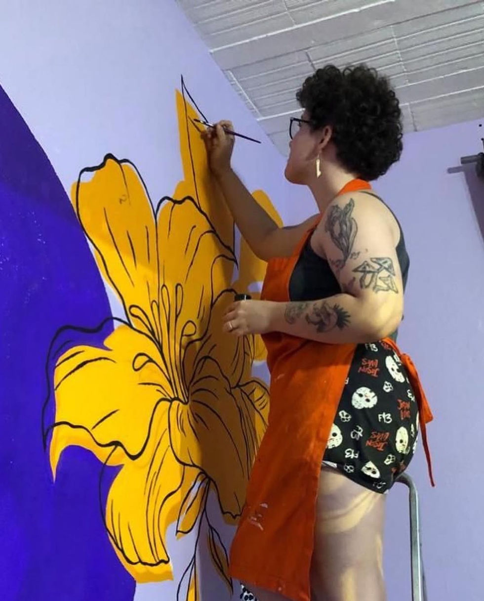 Alysson pintando uma das flores da parede botânica