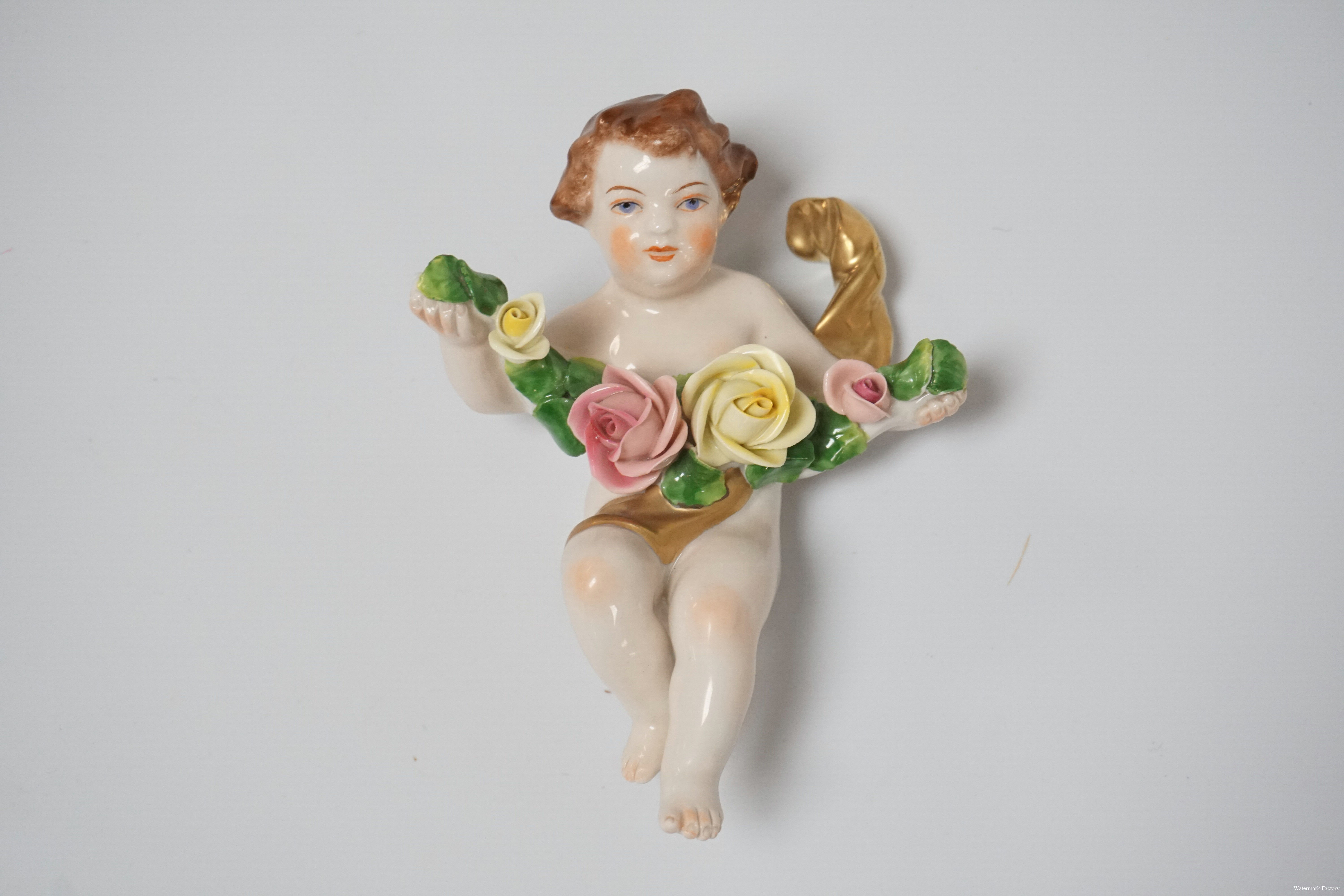 1038_RUDOLF KAMMER PORCELAIN WALL HANGING FIGURE OF A CHERUB WITH A STRING OF RO