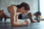 Woman performing plank with white sports bra on trying to prevent lower back pain in cycling