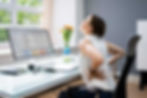 Woman experiencing lower back pain after sitting at her desk for 8 hours a day