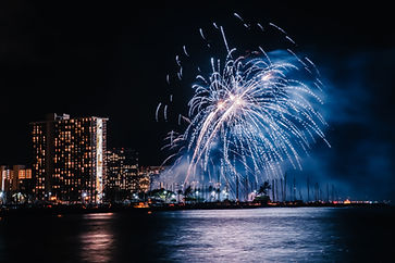 Vibrant pyrotechnic display dances above Waikiki, reflecting on Pacific waves, enchanting the night with brilliance.