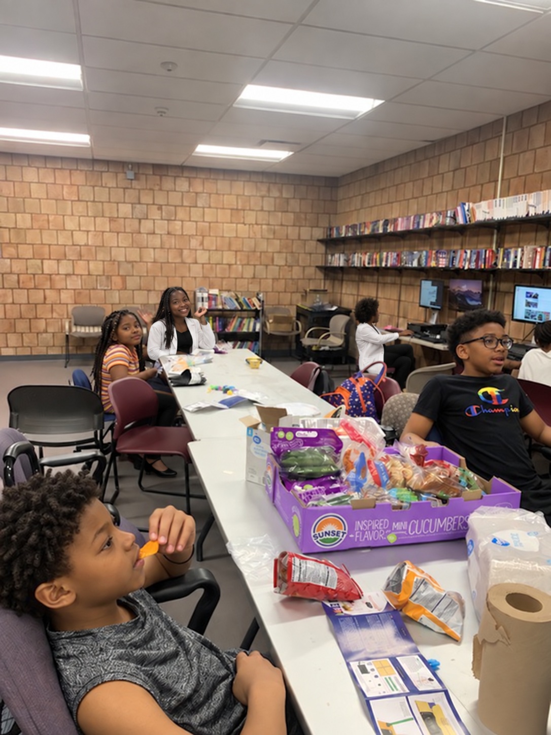 Students gathered around tables in a library activity space