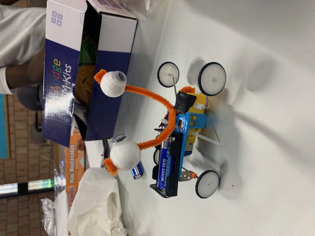 A handmade wheeled robot decorated with googly eyes