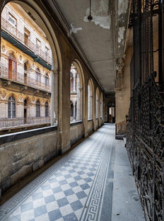 Historic Budapest gallery with patterned tile flooring, arched openings, ornate ironwork, and views into an interior courtyard.