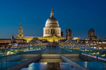 St. Paul's Cathedral photographed from Millennium Bridge in London, England, at blue hour with illuminated architecture and leading lines from the bridge.