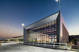 Modern terminal building at Sarasota-Bradenton International Airport in Sarasota, Florida, photographed at dusk, featuring contemporary architecture, expansive glass walls, and dramatic exterior lighting.
