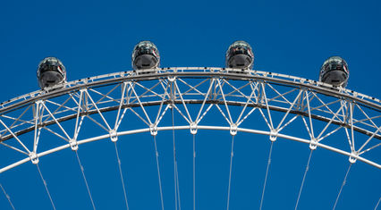 Close-up of the London Eye observation capsules in London, England, against a clear blue sky, showcasing the wheel's modern engineering and architectural design.
