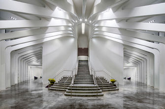 Interior of the Innovation, Science & Technology Building at Florida Polytechnic University in Lakeland, Florida, featuring soaring white structural beams, a symmetrical grand staircase, polished floors, and contemporary architectural design.