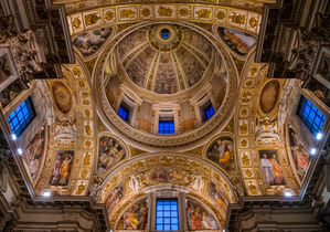 Looking up at the ornate dome of the Basilica di Santa Maria Maggiore in Rome, Italy, featuring intricate mosaics, gilded architectural details, decorative arches, and elegant Renaissance design.