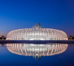The Innovation, Science & Technology Building at Florida Polytechnic University in Lakeland, Florida, reflected in a calm pool at twilight, featuring sweeping white structural architecture, dramatic symmetry, and a deep blue evening sky.