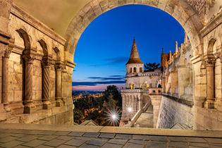 Twilight view of Matthias Church and Budapest framed by the stone arches of Fisherman's Bastion in Hungary, photographed by Randy Van Duinen during a European architectural photography workshop.