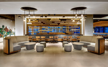 Modern cafeteria at Comcast in Philadelphia, Pennsylvania, featuring contemporary seating, wood architectural elements, pendant lighting, open dining areas, and a thoughtfully designed employee gathering space.