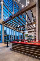 Interior of the club lounge at Raymond James Stadium in Tampa, Florida, featuring floor-to-ceiling glass walls, exposed steel beams, wood architectural accents, contemporary furnishings, and modern hospitality design.