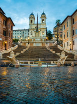 The Spanish Steps and Barcaccia Fountain in Rome, Italy, photographed at blue hour with Trinità dei Monti church illuminated above the historic staircase.