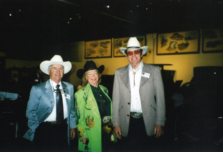 Three people in cowboy hats at car museum