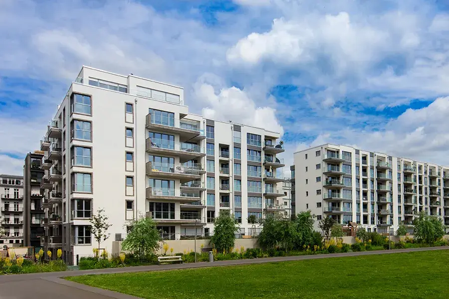 Modern white apartment blocks next to a park, showcasing contemporary leasehold developments.