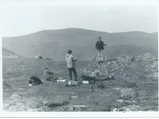 Black and white photo from 1964 of four men and a dog on Helvellyn summit.