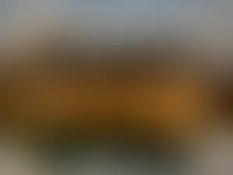 A scenic view of a castle perched on a high cliff and a white church at the edge of a calm lake with autumn reflections.