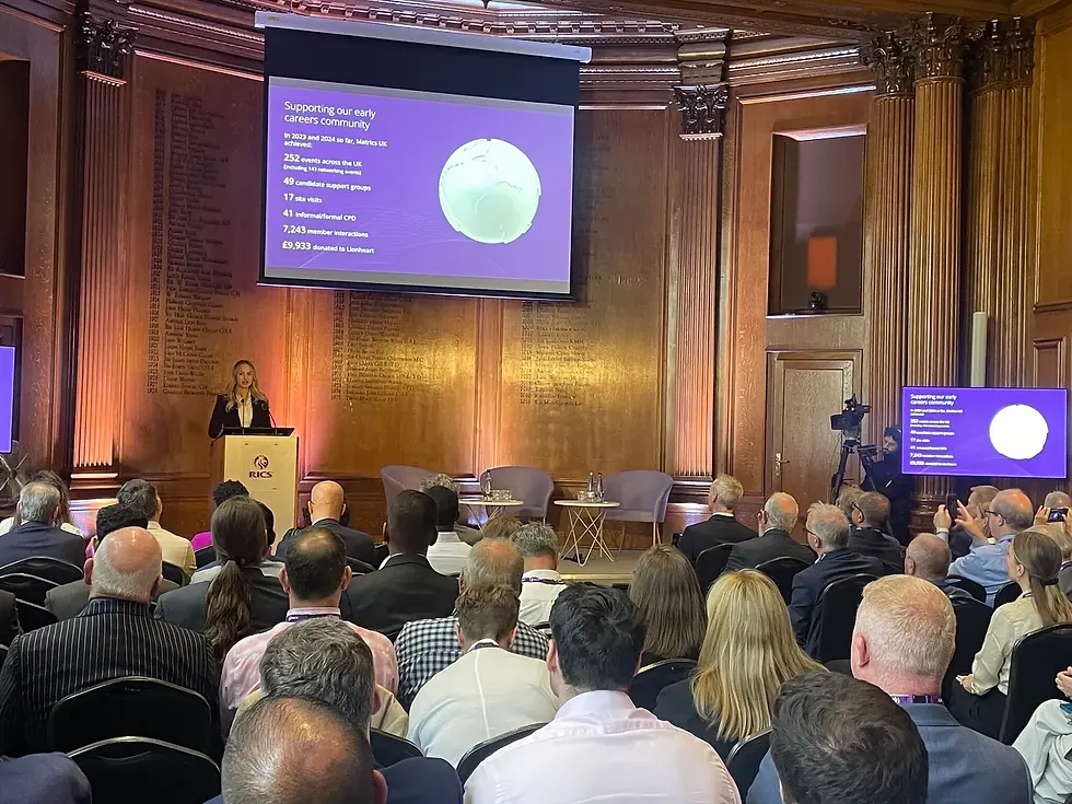 A presentation at an RICS early careers event showing community impact statistics to a seated audience