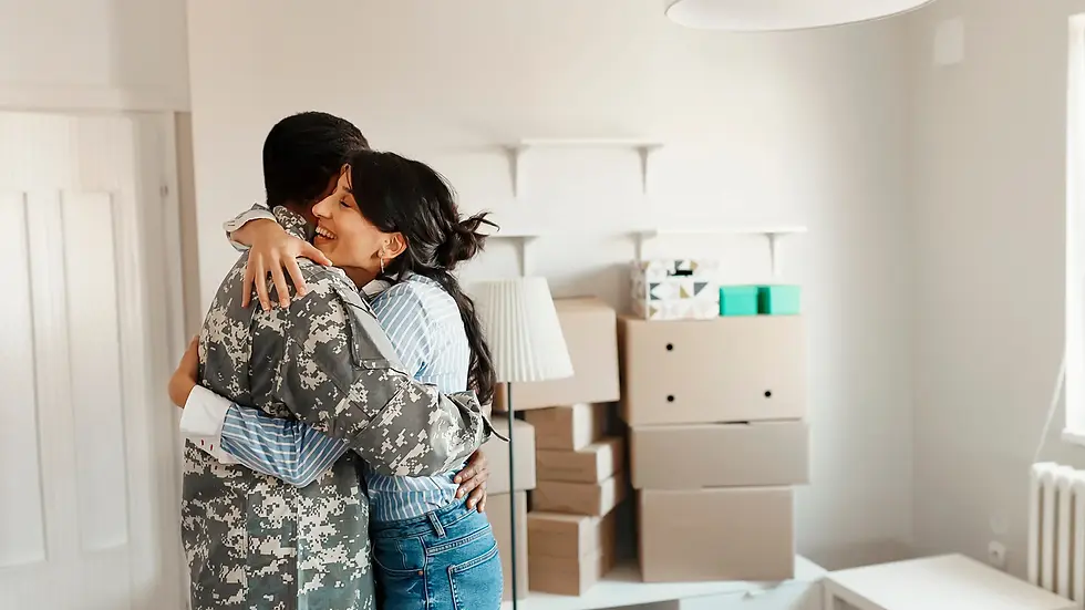 A young couple smiling and hugging while holding keys in their new home.