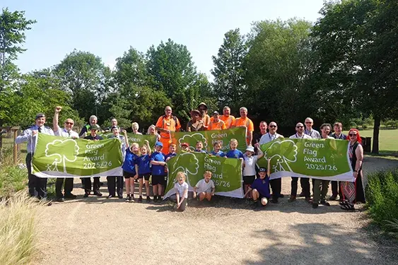 Chris Worman with two park gardeners in St James Park, London, with colorful flower beds and the Horse Guards building in the background.