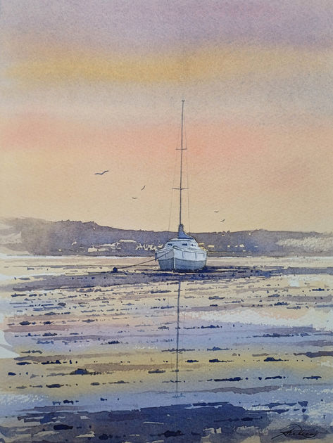 sunset over low tide where a boat can be seen resting on the sand