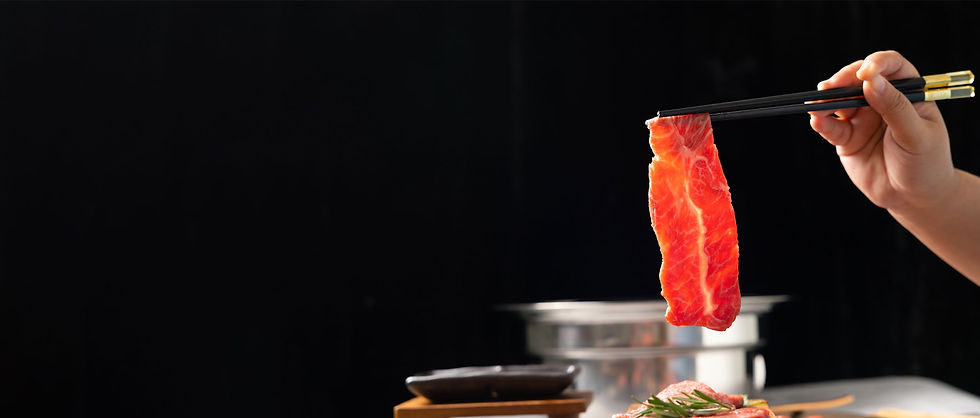A thin slice of Wagyu beef being held up with chopsticks