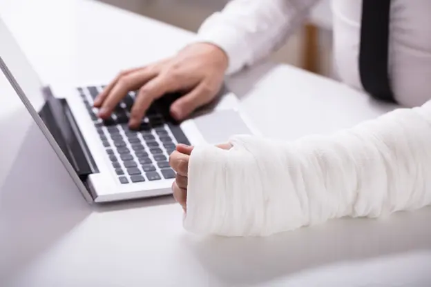 An injured man types on the laptop.