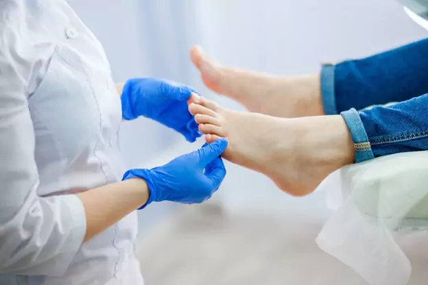  A foot care specialist examines a foot in a clinic.