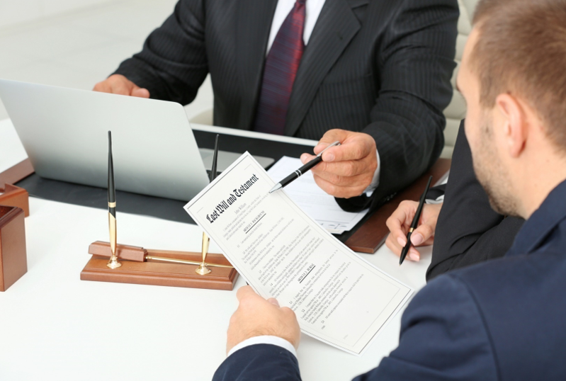 Close-up of a man holding a last will at a lawyer’s office.