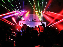 An electrifying atmosphere fills the nightclub as vibrant laser lights cut through the dark, highlighting the silhouette of a DJ energizing the lively crowd.