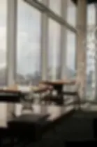 Sunlit restaurant with mountain view, wooden tables set with glasses, napkins, and cutlery. Silver bauble decorations hang by large windows.