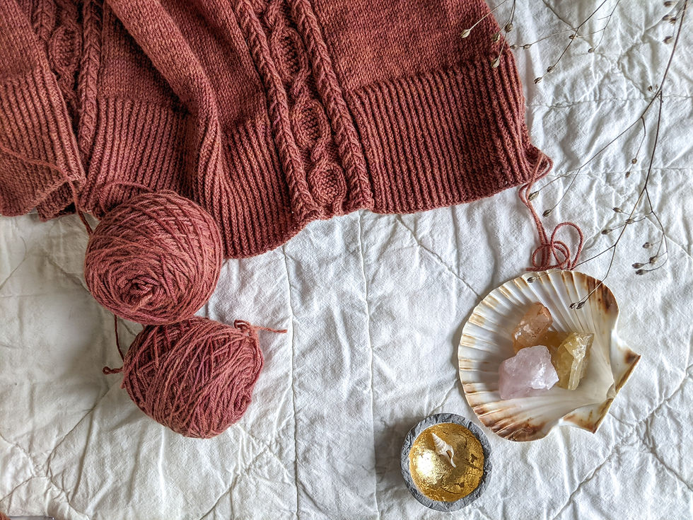 A rich pink-red-rust colored sweater hem, with a deep rib and a textured cable.