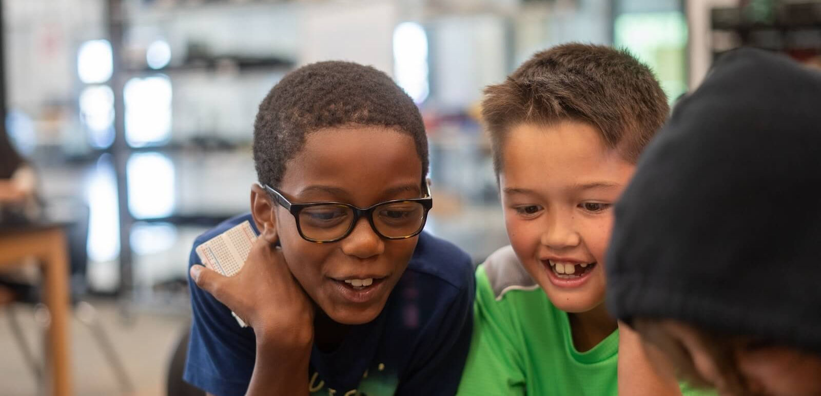 Three cheerful students looking at a screen together. Student Experiences and PAST Foundation.