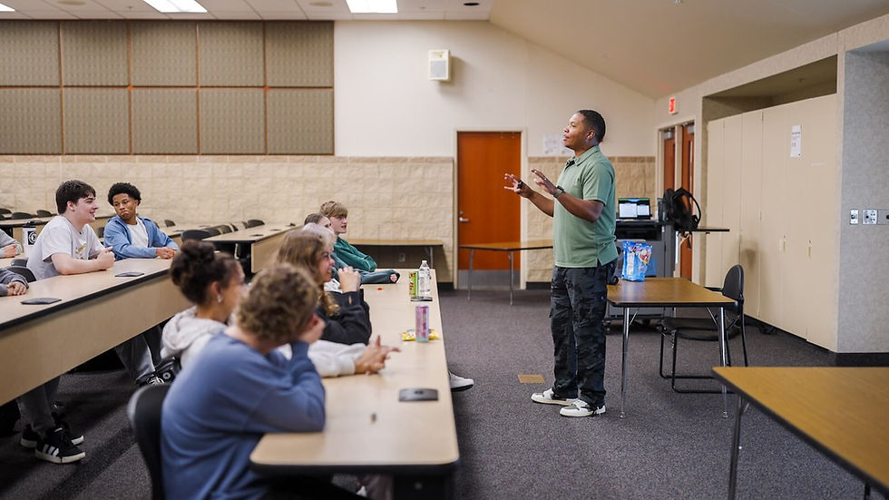 Instructor speaking to a class of students in a lecture hall.