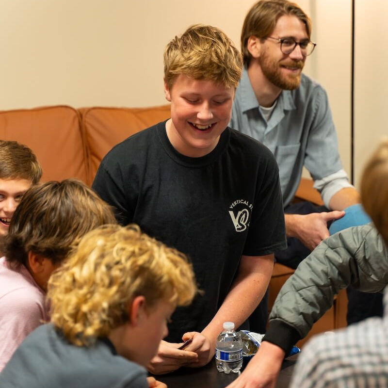 Smiling young man with friends playing a game at youth group