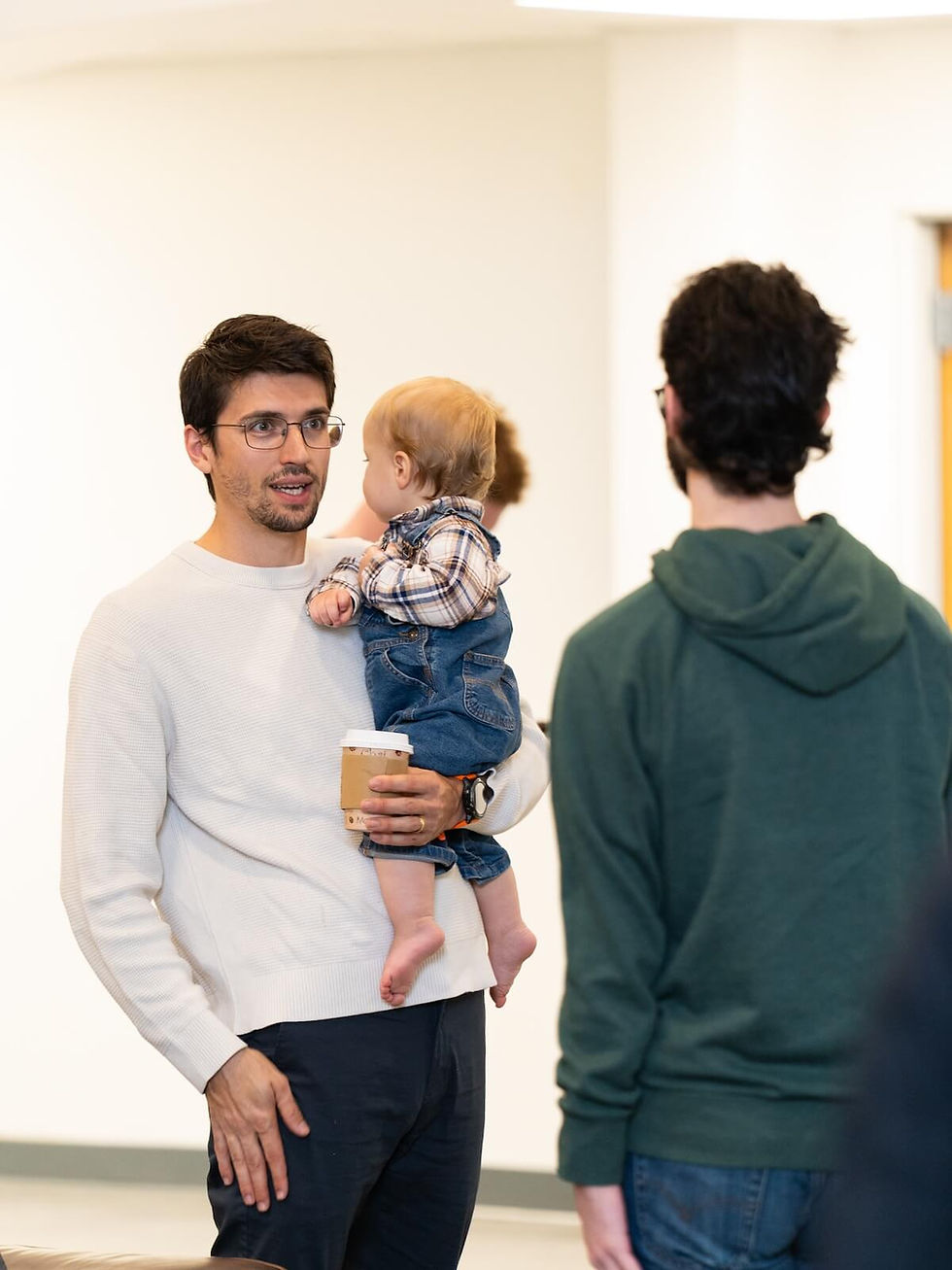 Man in glasses holding baby while having joyful conversation