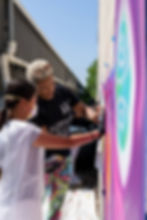 Two women painting a mural outdoors with spray paint; Active Artists, PAST Foundation