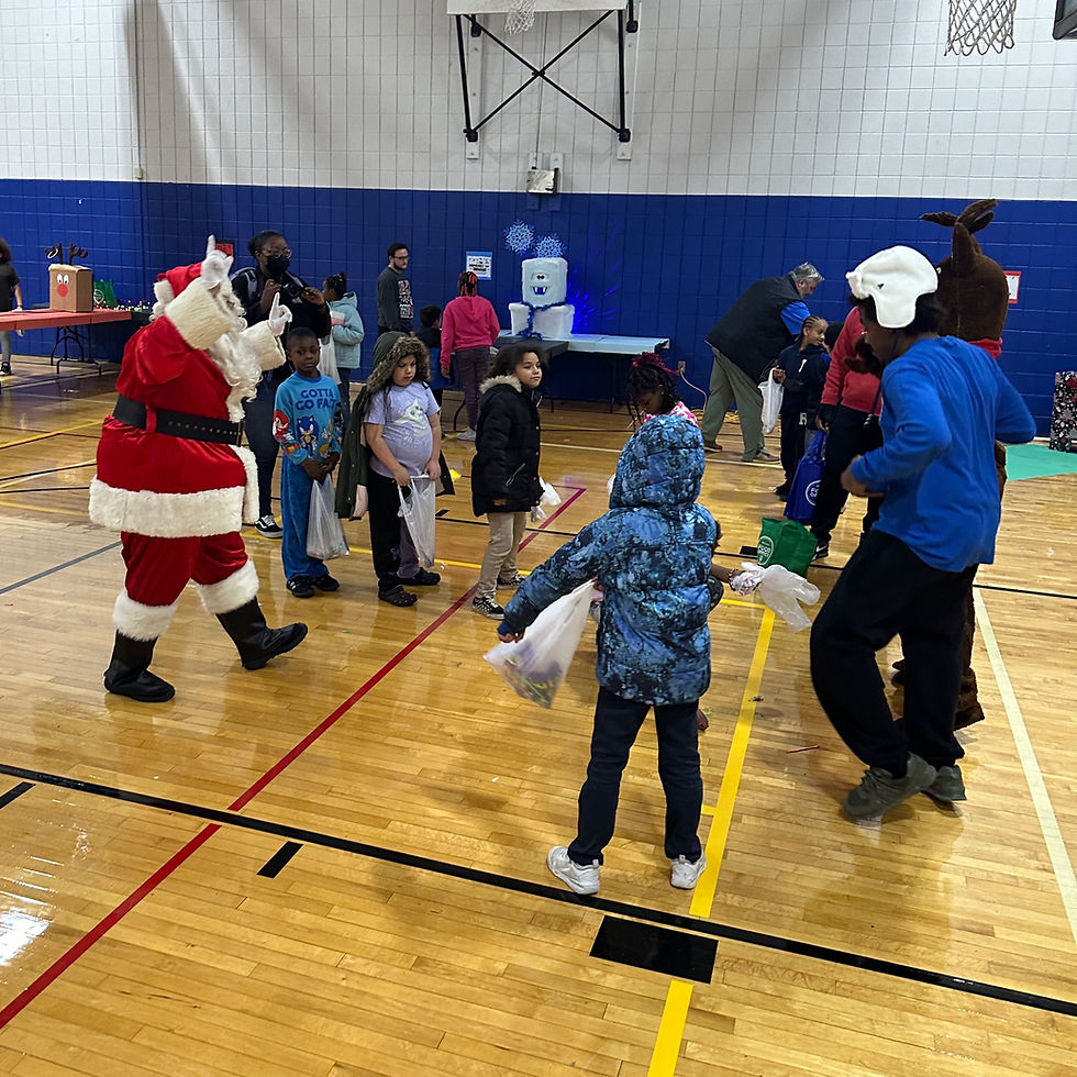 Santa and kids gather in a gym, holding gift bags. A person in a bear costume joins the fun. Festive and playful atmosphere.