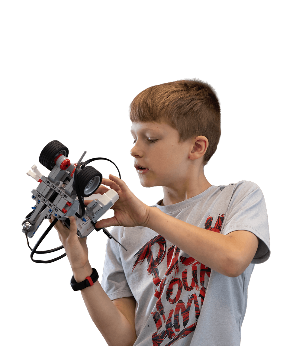 Young boy building a gray Lego car, focused on mechanics, during a workshop.