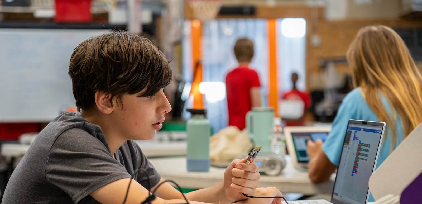Young student works on robot alongside classmates with littlebits.cc on laptop.