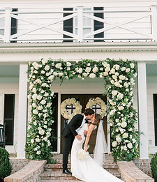 Wedding arch decorated with white flowers and greenery draping for a ceremony backdrop.