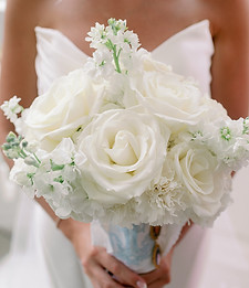 Elegant white rose bridal bouquet with soft greenery and neutral floral accents.