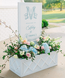 Welcome sign in floral box with soft blue and pink florals with greenery.