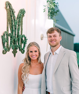Large White Petitions with sconces used as stage backdrop with a moss monogram crest placed in the center.