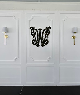 Large White Petitions with sconces used as stage backdrop with a moss monogram crest placed in the center.