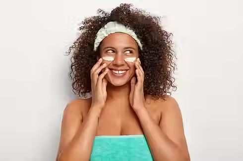 mulher-bonita-e-alegre-aplica-cosmeticos-para-o-rosto-olha-alegremente-para-o-lado-usa-ban