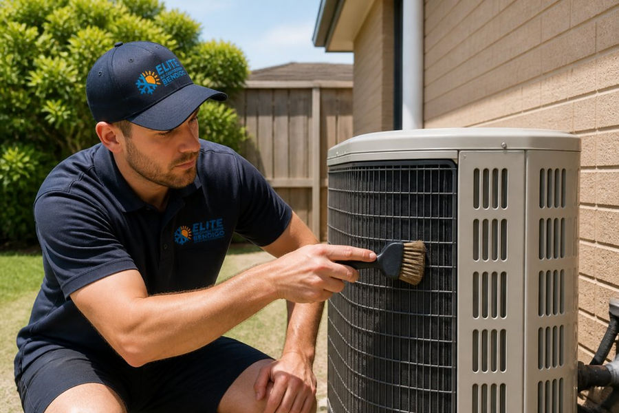 A technician in uniform cleaning the outdoor unit of a reverse-cycle air conditioner with a brush, on a sunny day in a suburban backyard
